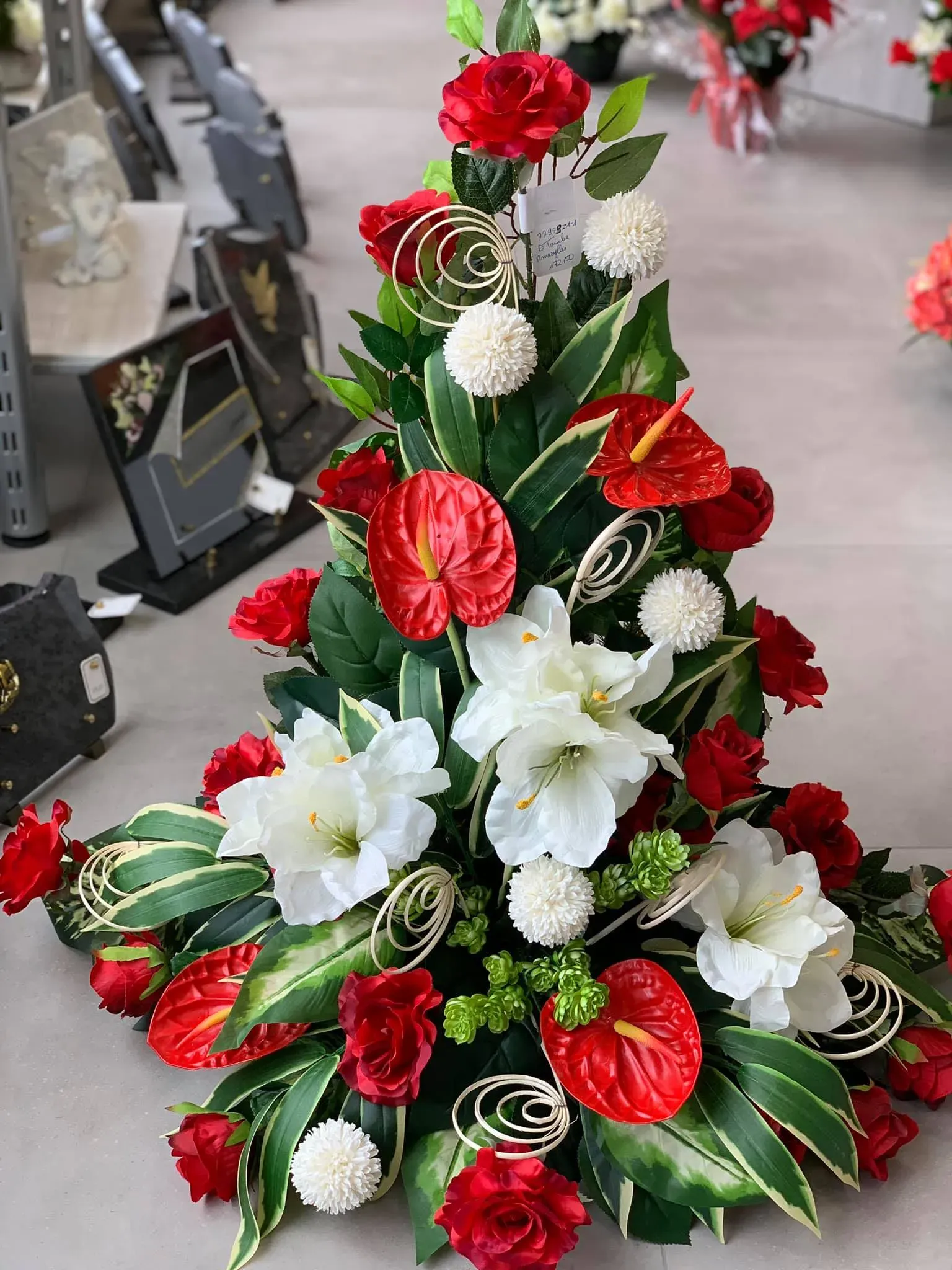 Composition florale funéraire avec anthuriums rouges et lys blancs.