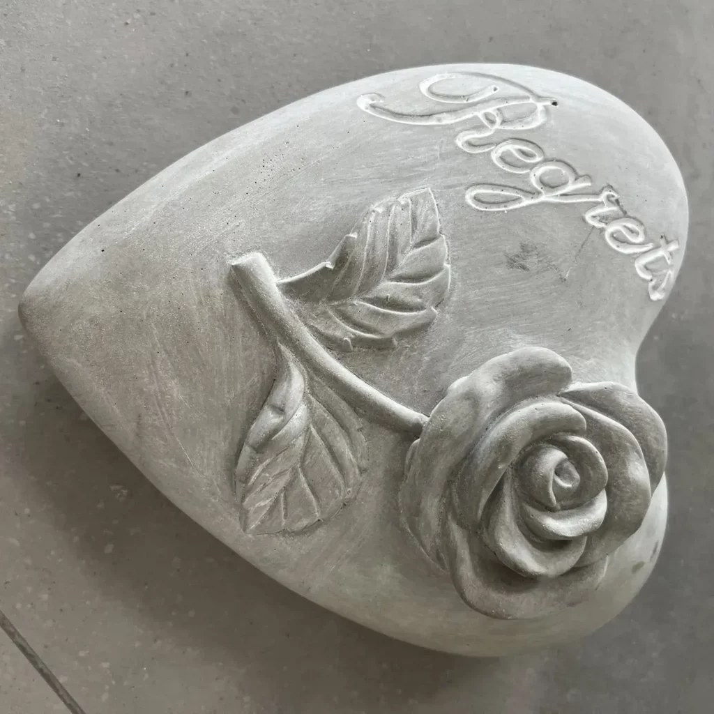 Plaque funéraire en pierre en forme de cœur gravée avec une rose.