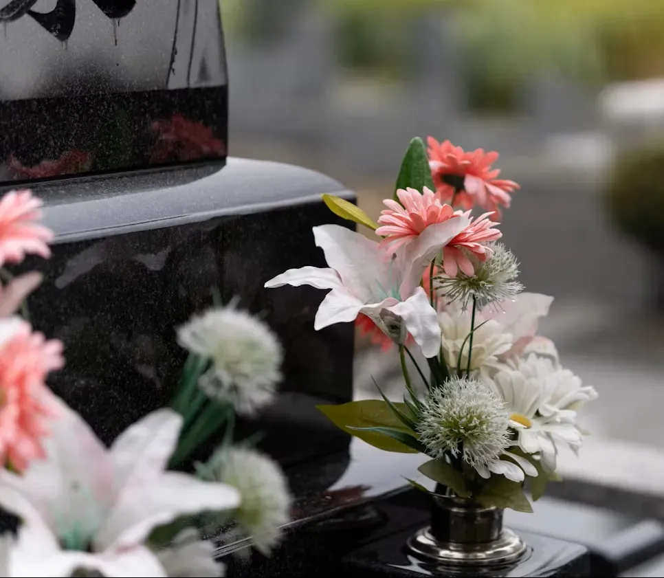 Fleurs de deuil déposées sur une pierre tombale en granit noir.