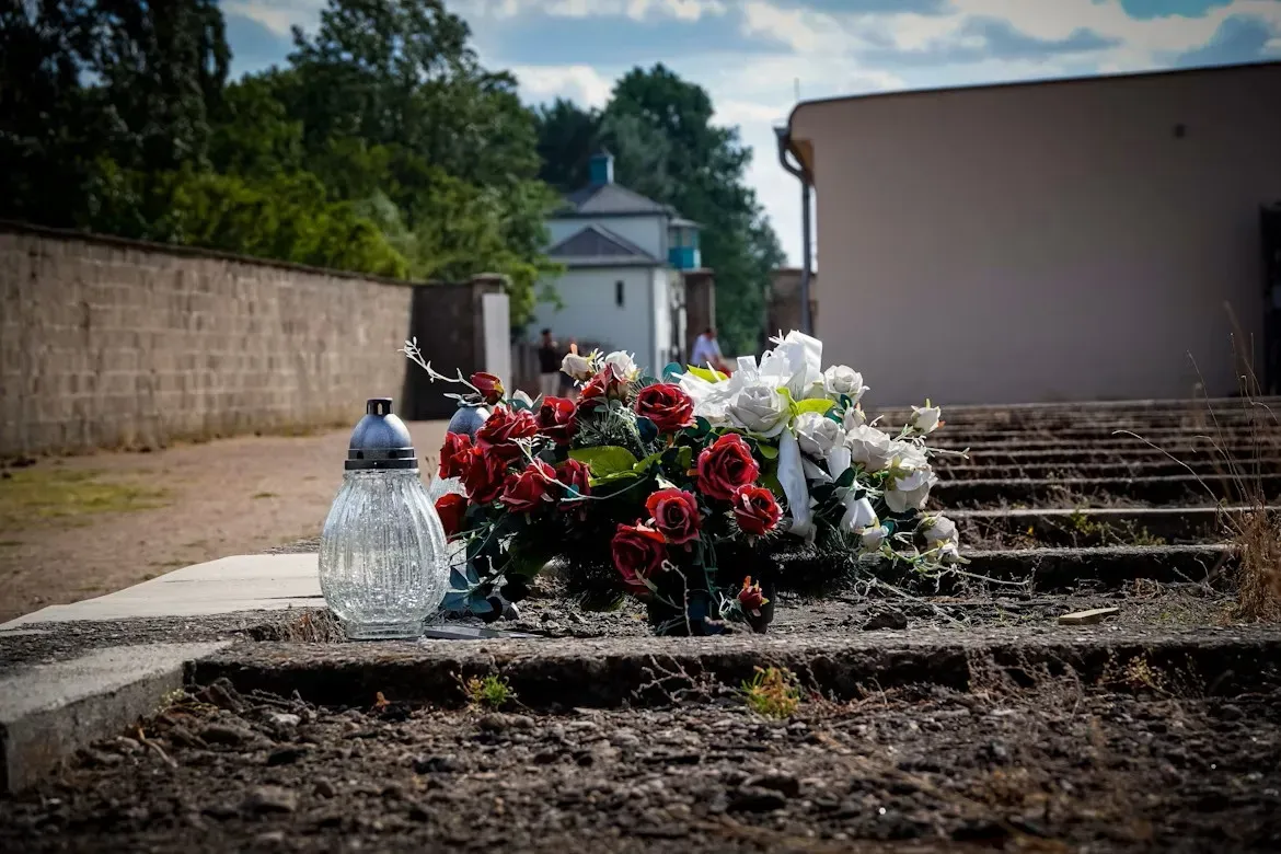 Fleurs commémoratives et bougie déposées sur une sépulture au cimetière.
